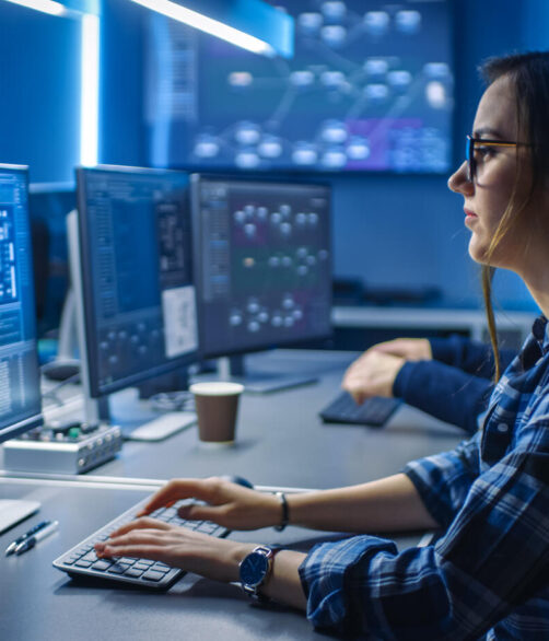 Smart Young Female IT Programer Working on Desktop Green Mock-up Screen Computer in Data Center System Control Room. Team of Young Professionals Programming Sophisticated Code